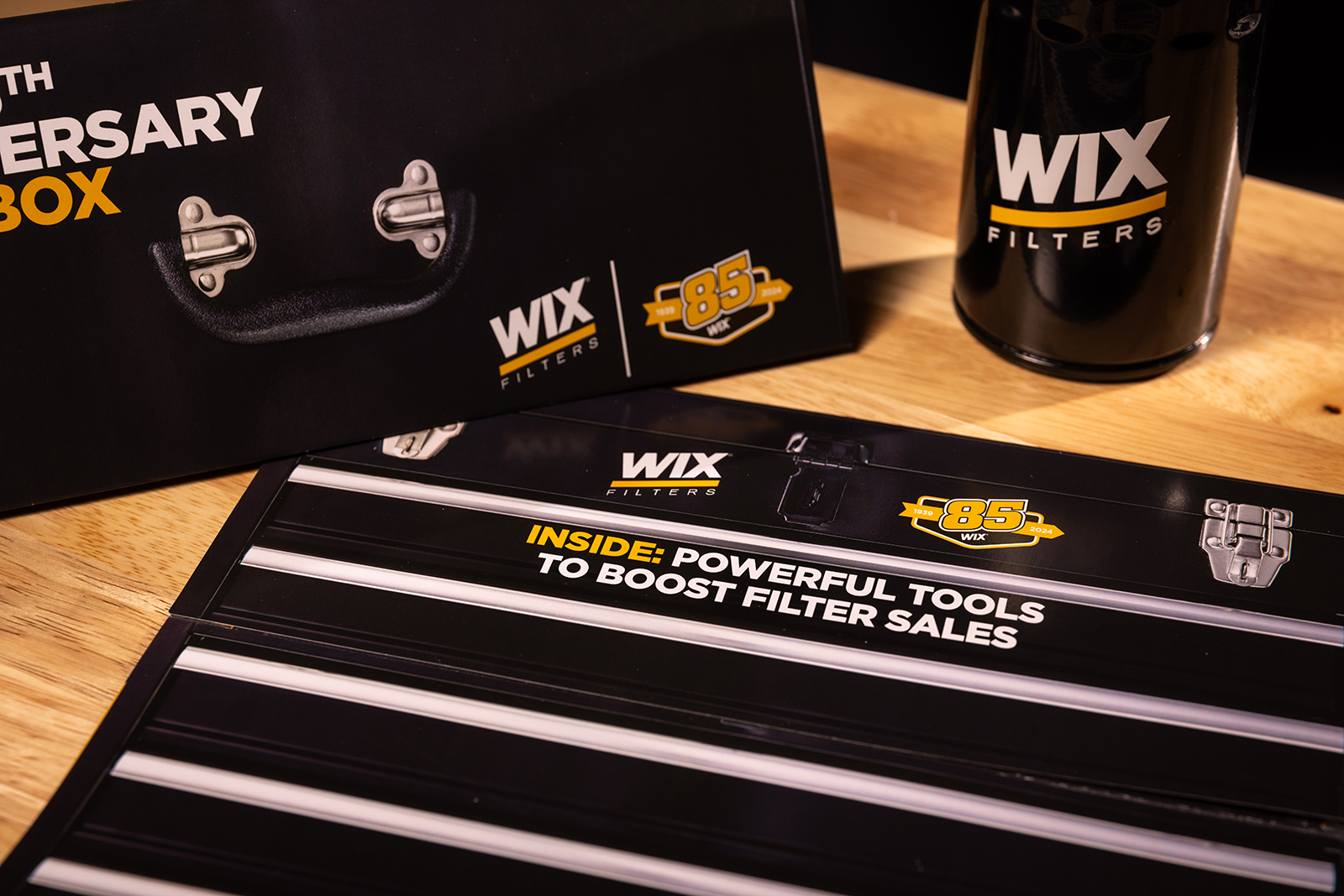 WIX Filters 85th Anniversary toolbox-themed brochure displayed on a wooden workbench alongside a branded WIX filter.