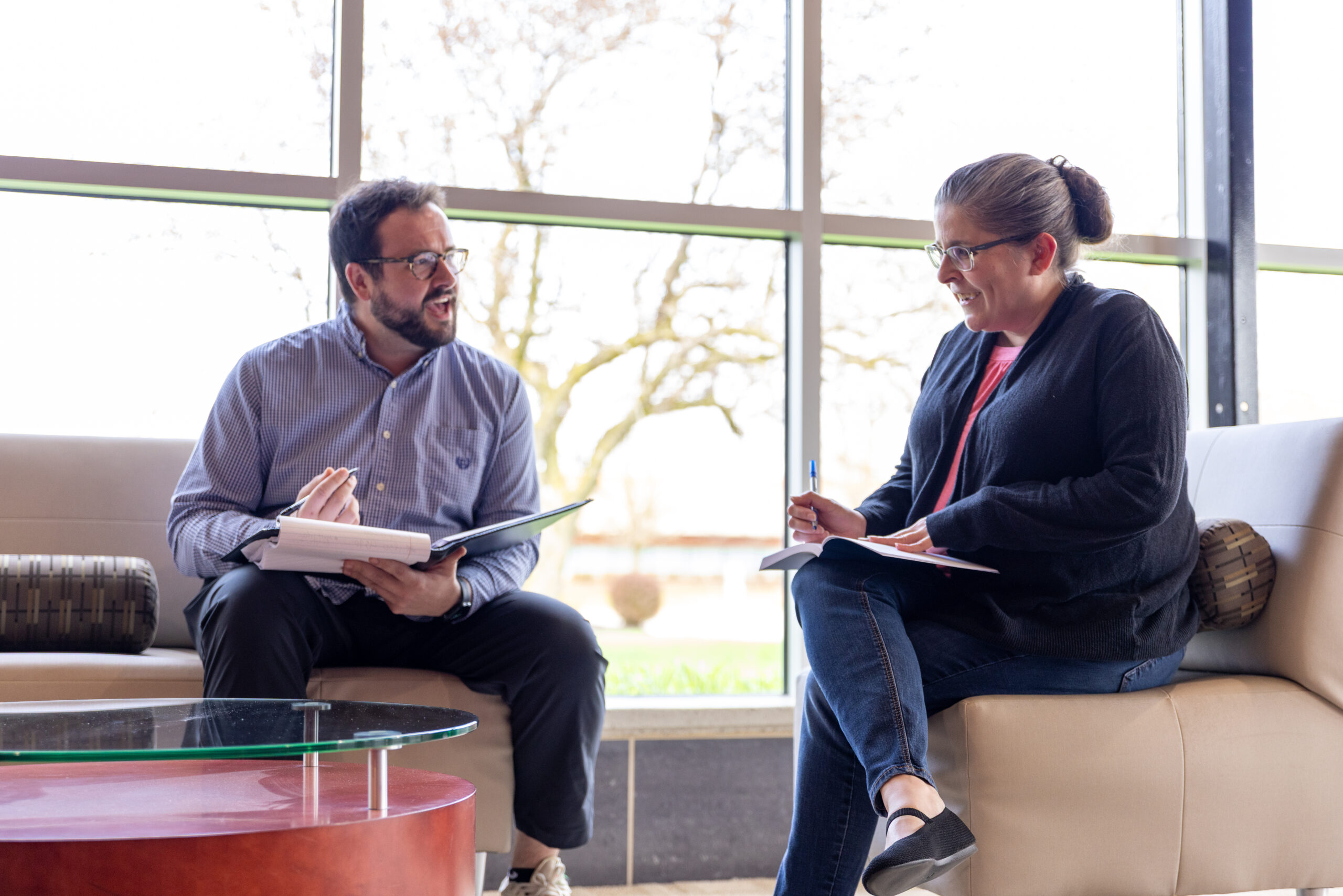 Two people working and meeting with notebooks in a sunny atrium